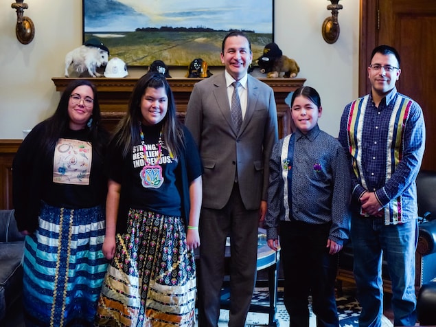 Theo Osborne et sa famille avec le premier ministre du Manitoba, Wab Kinew, souriant tous à la caméra, dans son bureau.