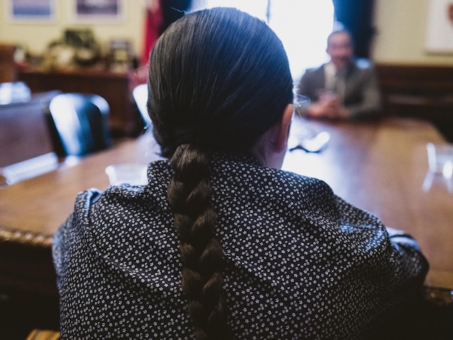Le jeune Theo Osborne assit de dos à une table en face du premier ministre du Manitoba, Wab Kinew.