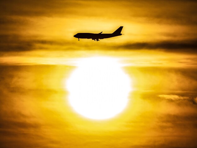 La silhouette d'un avion au-dessus du soleil qui se lève.