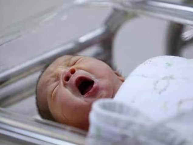 Un bébé pleure dans un lit à l'hôpital. 