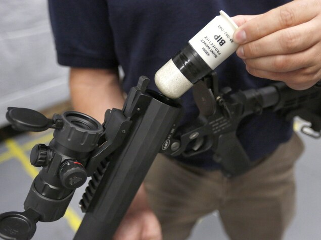 Une personne insère un projectile de type BIP dans une arme d'impact. Une personne insère un projectile de type BIP dans une arme d'impact.