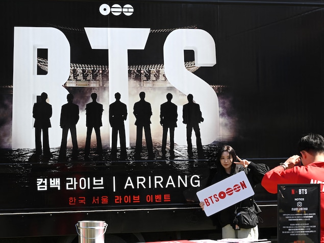 Une femme pose pour une photo devant un camion faisant la promotion du concert de retour du groupe de pop coréenne BTS à Séoul, le 19 mars 2026.