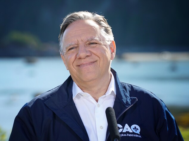 François Legault sourit devant une étendue d'eau. 