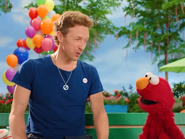Chris Martin discute avec le personnage Elmo de Sesame Street.