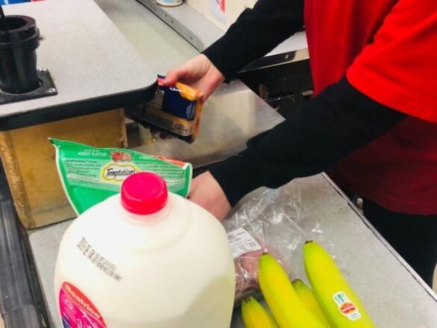 Une caissière scanne des aliments dans une épicerie.