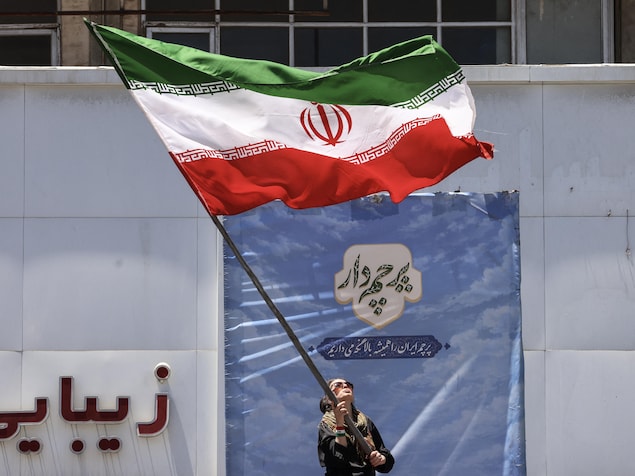 Une femme iranienne brandit le drapeau national à Téhéran, le 15 juin 2026.