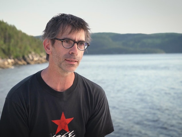 On voit M. Bourgault, de face, qui parle à la caméra. En arrière-plan, on voit le fjord du Saguenay. On voit M. Bourgault, de face, qui parle à la caméra. En arrière-plan, on voit le fjord du Saguenay.