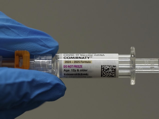 Un pharmacien tient une dose de vaccin,