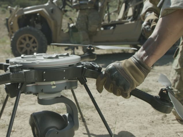 Un homme vêtu en tenu militaire assemble un drone.