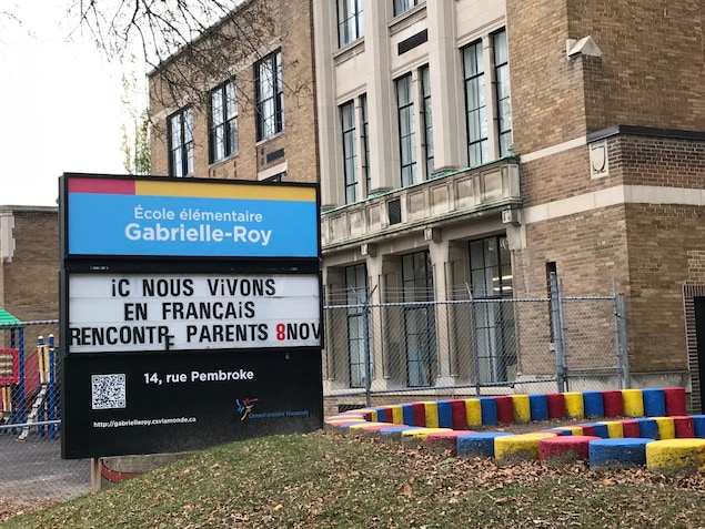 Sur un panneau devant l'immeuble est écrit : « Ici nous vivons en français ». Sur un panneau devant l'immeuble est écrit : « Ici nous vivons en français ».