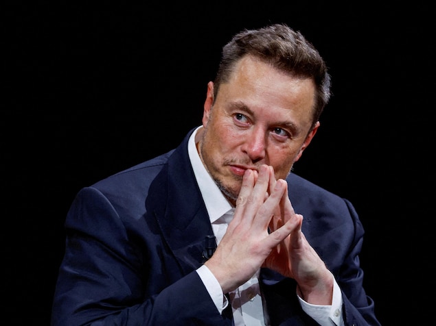 Elon Musk écoute, les deux mains en prière devant la bouche.