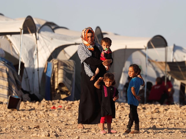 L'un des enfants est dans les bras de la femme, au centre de la photo. L'un des enfants est dans les bras de la femme, au centre de la photo.