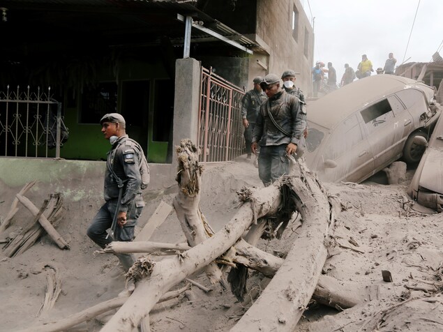 Des policiers traversent les décombres et les débris dans une rue de la ville d'Escuintla, au Guatemala, après l'éruption du volcan de Fuego. Des policiers traversent les décombres et les débris dans une rue de la ville d'Escuintla, au Guatemala, après l'éruption du volcan de Fuego.