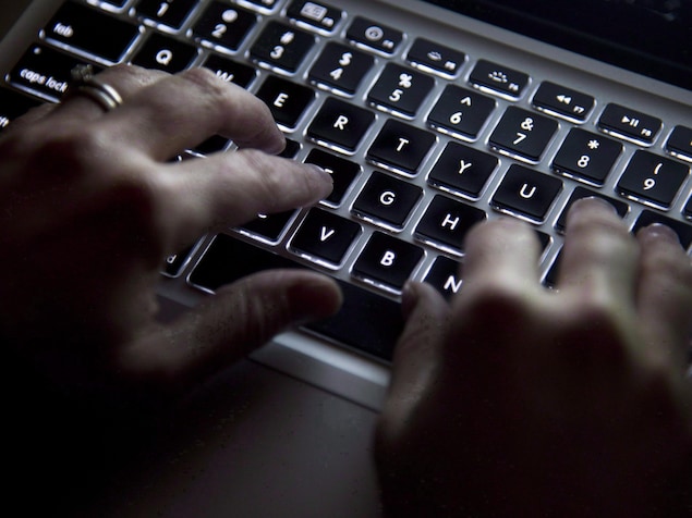 Des mains devant un clavier d'ordinateur.