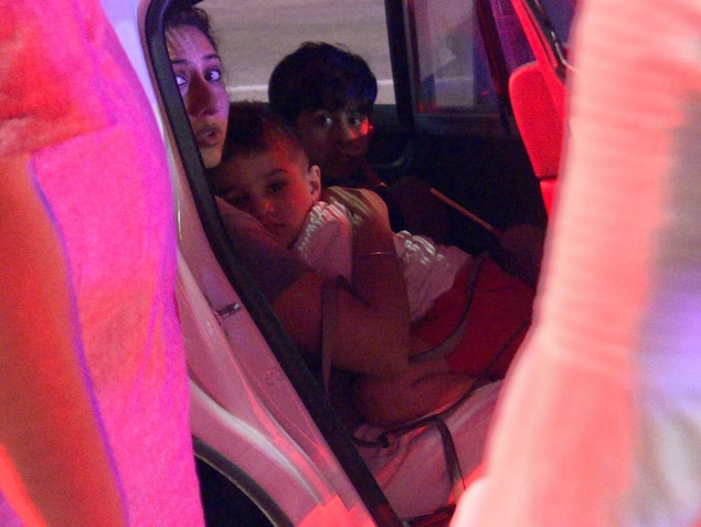 Une femme et deux enfants sont installés à l'arrière d'un véhicule, dans le stationnement du restaurant Bombay Bhel. Une femme et deux enfants sont installés à l'arrière d'un véhicule, dans le stationnement du restaurant Bombay Bhel.