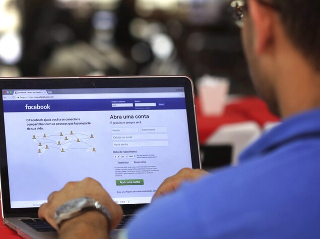 Un homme au clavier d'un ordinateur se branche sur le réseau social Facebook. Un homme au clavier d'un ordinateur se branche sur le réseau social Facebook.