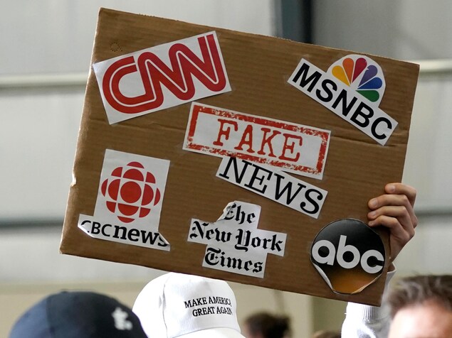 Un partisan du président Donald Trump brandit une pancarte associant les fausses nouvelles à des médias tels que CNN, le CBC News et le New York Times.