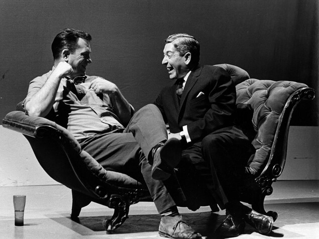Dans un studio de télévision, Jack Kerouac et Fernand Seguin, riant, sont assis sur une causeuse. Dans un studio de télévision, Jack Kerouac et Fernand Seguin, riant, sont assis sur une causeuse.