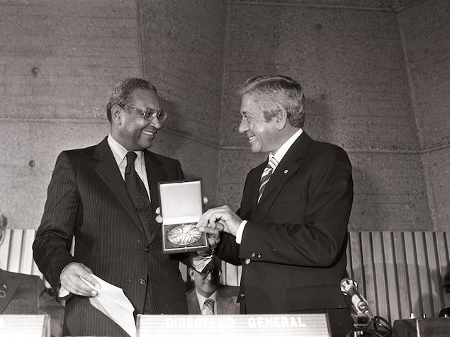Fernand Seguin, tout sourire, recevant une médaille dans un coffret des mains d'Amadou-Mahtar M'Bow. Fernand Seguin, tout sourire, recevant une médaille dans un coffret des mains d'Amadou-Mahtar M'Bow.