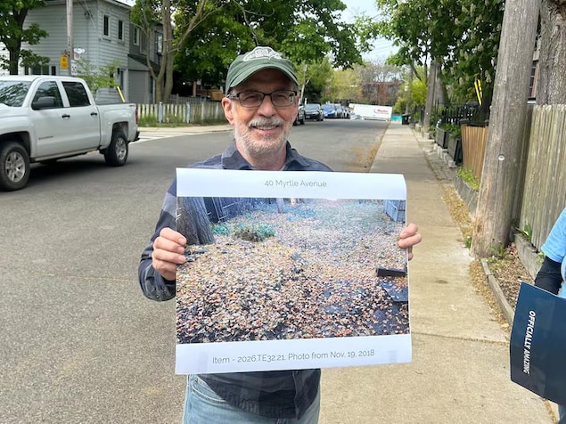 Alan Page tient une photo des fruits du ginkgo qui jonchent son jardin chaque automne.