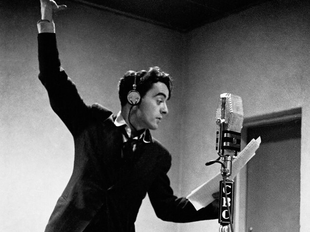 Dans un studio de radio, derrière un microphone sur pied, Guy Mauffette s'exprime, les bras en l'air. Dans un studio de radio, derrière un microphone sur pied, Guy Mauffette s'exprime, les bras en l'air.