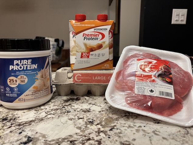 Des aliments protéines sur un comptoir (poudre protéinée, œufs, viande rouge et boisson protéinées)