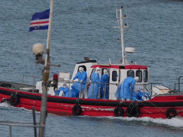 Des gens en combinaison de protection sur un bateau rouge.