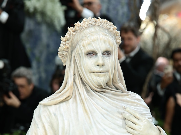 Une femme costumée de façon très réaliste en statue pose, immobile, pour une photo.