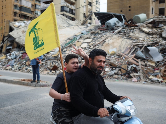 Un jeune brandit le drapeau du Hezbollah en passant devant des immeubles détruits dans la banlieue sud de Beyrouth.
