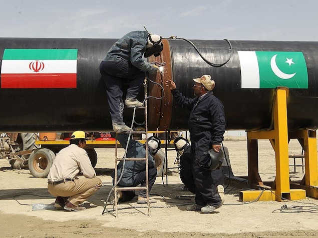 Des ouvriers travaillent à souder deux bout d'un pipeline.