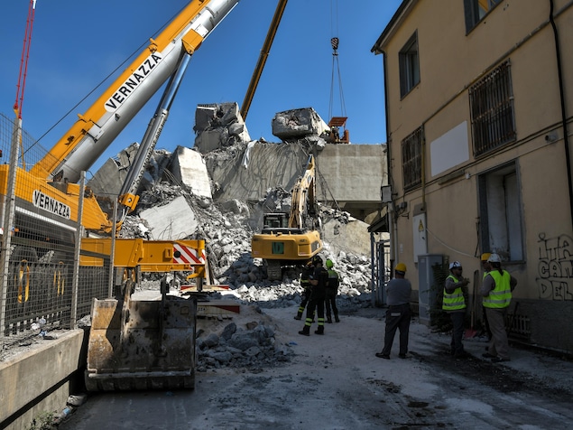 Des grues et pelles mécaniques, qui se trouvent près de secouristes, semblent soulever des gros morceaux de béton. Des grues et pelles mécaniques, qui se trouvent près de secouristes, semblent soulever des gros morceaux de béton.
