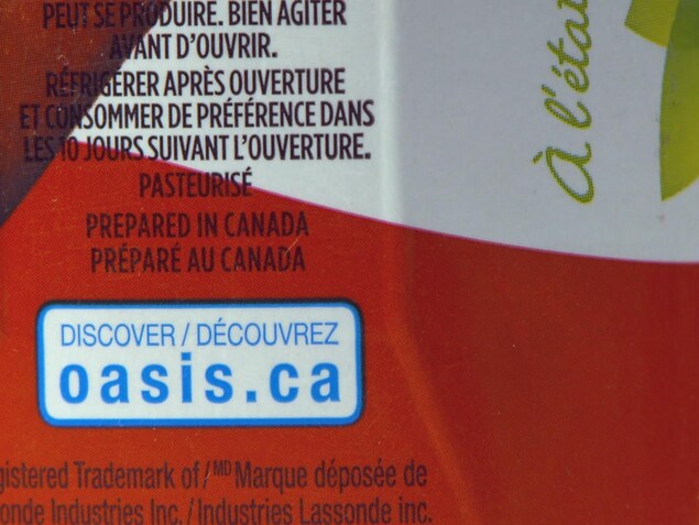 On voit en gros plan la mention « Préparé au Canada » sur l'emballage d'un jus de pomme de marque Oasis. On voit en gros plan la mention « Préparé au Canada » sur l'emballage d'un jus de pomme de marque Oasis.