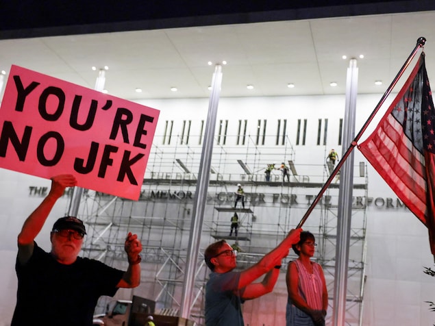Des hommes tiennent un drapeau et une pancarte devant le Kennedy Center.