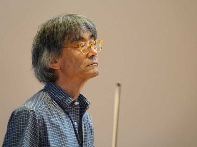 Le maestro, baguette en main, les yeux fermés, l'air concentré. Le maestro, baguette en main, les yeux fermés, l'air concentré.