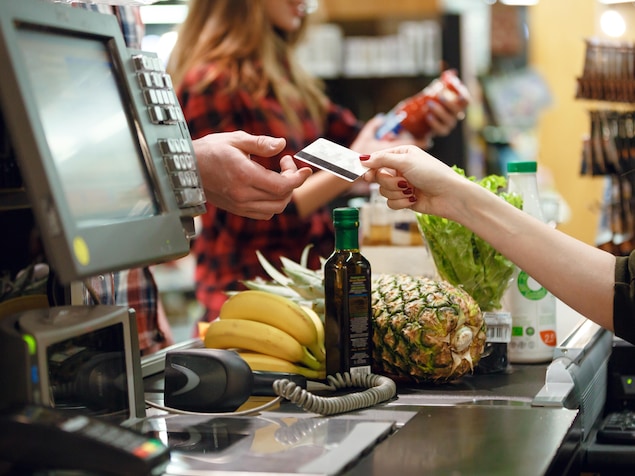 Une personne donne une carte à la caisse d'une épicerie.