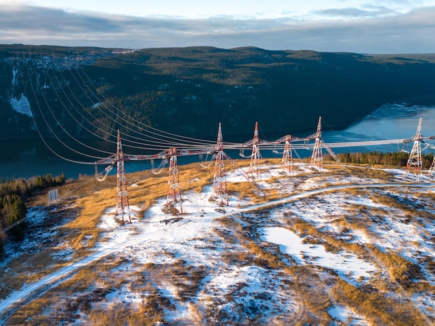 Des lignes électriques traversent un fleuve pendant l'hiver.