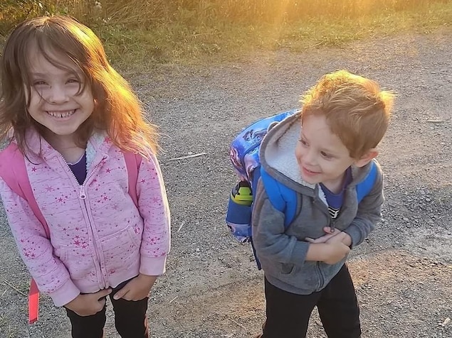 Deux enfants souriants le long d'une route rurale.