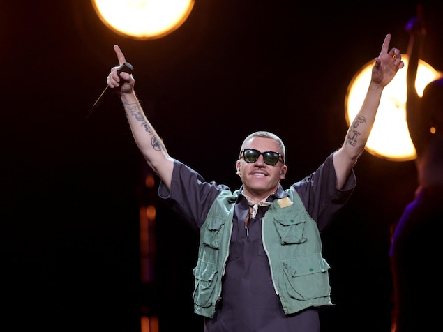 Macklemore sur scène les bras dans les airs.