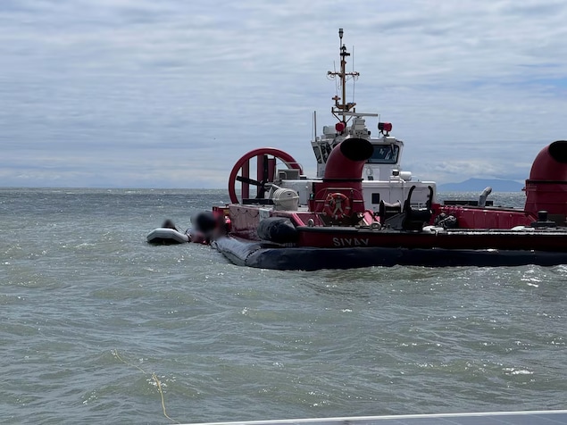 Un canot pneumatique est à côté d'un bateau de la Garde côtière.
