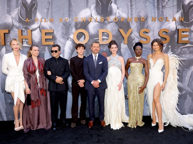 Des acteurs et actrices posent devant un mur présentant des images du film L'Odyssée.