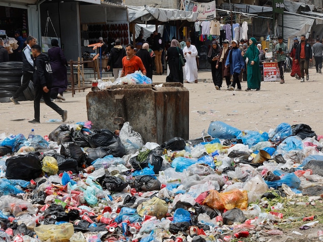 Des Palestiniens passent devant des tas d'ordures et de déchets près des tentes destinées aux personnes déplacées, alors que les rongeurs prolifèrent, à Khan Younès.