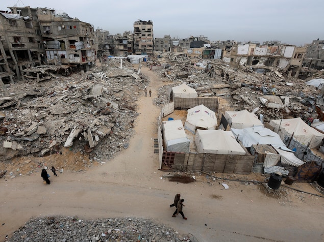Des Palestiniens passent devant les décombres d'immeubles d'habitation détruits par la guerre.