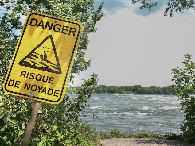 Un panneau «risque de noyade» planté près du fleuve Saint-Laurent à Montréal.