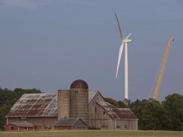Une éolienne et une grue derrière une grange. Une éolienne et une grue derrière une grange.