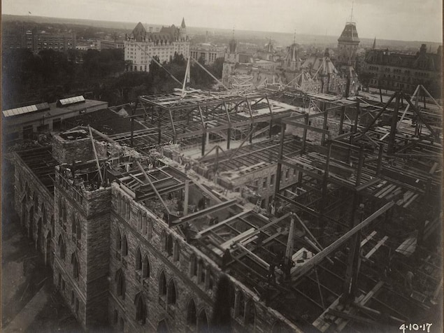 Vue en plongée au-dessus de l'édifice du parlement en reconstruction, en 1917. On voit la charpente des murs et du toit. Vue en plongée au-dessus de l'édifice du parlement en reconstruction, en 1917. On voit la charpente des murs et du toit.