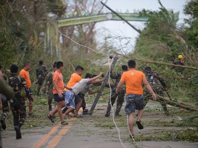 Des secouristes tentent de dégager la route, bloquée par des arbres et des poteaux d'électricité qui sont tombés sous les vents du super typhon Mangkhut. Des secouristes tentent de dégager la route, bloquée par des arbres et des poteaux d'électricité qui sont tombés sous les vents du super typhon Mangkhut.