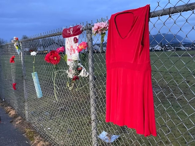 Une robe rouge et des fleurs sont attachés à une cloture qui entoure le terrain de la ferme de Robert Pickton. 