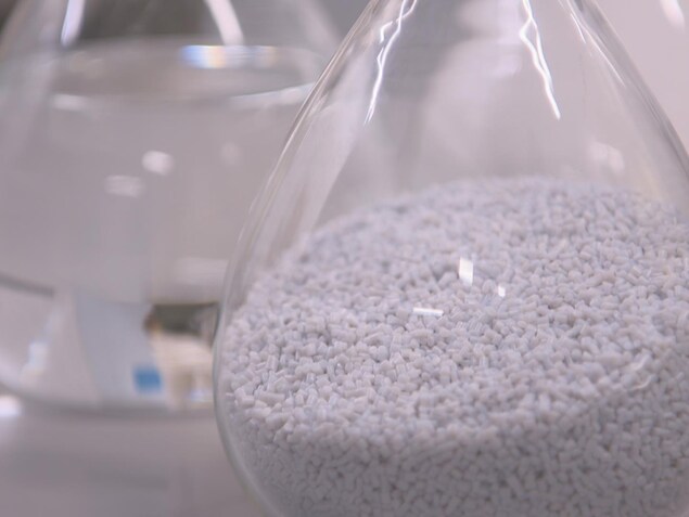 On voit en gros plans des granules de plastique dans une fiole erlenmeyer. On voit en gros plans des granules de plastique dans une fiole erlenmeyer.