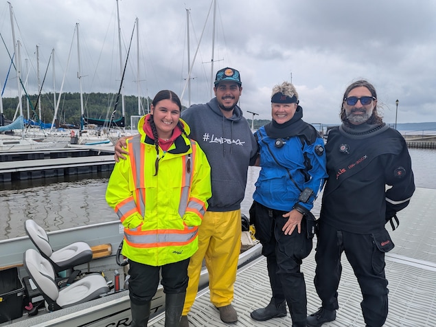 Quatre personnes posent pour la photo sur un quai de bateaux.