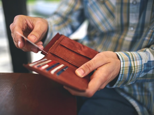 Une personne sort une carte d'un portefeuille.